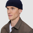 En mann har på seg en marineblå ulllue i et klassisk, ribbet skandinavisk design.