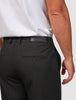 En person som har på seg en hvit T-skjorte som er stappet inn i svarte Essential Suit Pants i avslappet passform med en lærlapp med merke.
