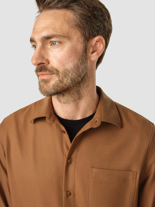 En mann har på seg en Casual Shirt i fargen Camel over en svart T-skjorte.