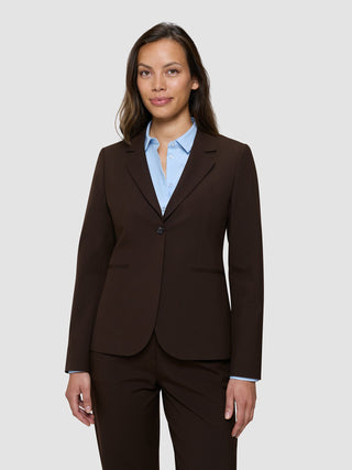 En kvinne som har på seg en «Women’s Essential Fitted Blazer» i fargen «Espresso» over en lyseblå skjorte med knapper.