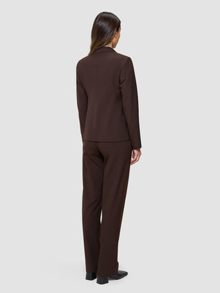 En kvinne sett bakfra, kledd i en «Women’s Essential Fitted Blazer» i fargen «Espresso» og matchende bukser i skandinavisk design.
