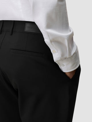En person som har på seg en hvit skjorte med knapper, stappet inn i Essential Shorts Black.