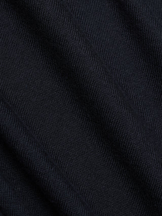 Et nærbilde av de myke foldene på en svart, fint strikket turtleneck.