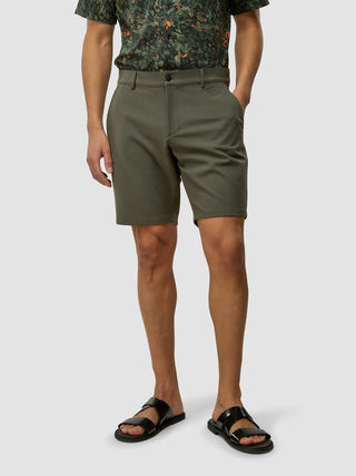 En mann kledd i en mønstret kortermet skjorte, GEN2™-shorts i fargen «Muted Green» og svarte sandaler.