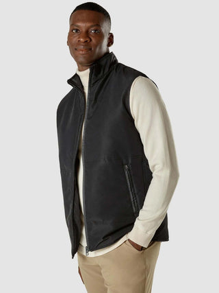 En mann har på seg en svart Utility-vest over en kremfarget turtleneck.