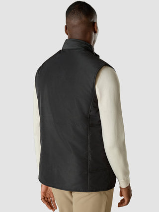 En mann sett bakfra, kledd i en svart Utility Vest over en kremfarget skjorte med lange ermer.
