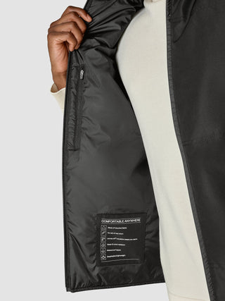 Nærbilde av innsiden av Utility Vest Black, som viser en etikett med opplysninger om resirkulert stoff, PrimaLoft-isolasjon og en glidelås.