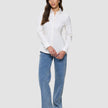 En kvinne iført en Women’s Oxford Shirt White Orchid Slim, som hun har stappet inn i lyseblå jeans og svarte loafers.