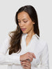 En kvinne i en Women’s Oxford Shirt White Orchid Slim ser ned mens hun retter på mansjetten.