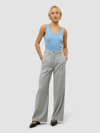En kvinne har på seg en lyseblå tank-top og «Women’s Skye Pants Wide Grey Pine Melange» i skandinavisk design.