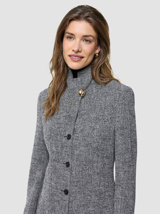 En kvinne som har på seg en «Ashryn Set Domino Herringbone Blazer» med en iøynefallende gullknapp ved halsen.