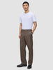 En mann har på seg en hvit T-skjorte, Atelier Pants Relaxed Dark Beige og svarte sko.