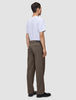 En person sett bakfra, kledd i en hvit T-skjorte og mørkbeige Atelier Pants Relaxed.