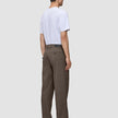 En person sett bakfra, kledd i en hvit T-skjorte og mørkbeige Atelier Pants Relaxed.