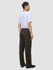 En person sett fra siden, kledd i en hvit T-skjorte og Atelier Pants Relaxed Dark Brown i brutt twill.