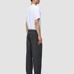 En mann sett i profil har på seg en hvit T-skjorte og Atelier Pants Relaxed Dark Grey i mørkegrå, løstsittende brutt twill.