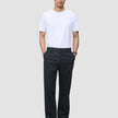 En mann i hvit T-skjorte, mørk marineblå Atelier Pants Relaxed og svarte loafers, som gjenspeiler det rene skandinaviske designet.