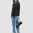 En kvinne kledd i en svart Women’s Avira Blazer og blå jeans, med en svart skulderveske.