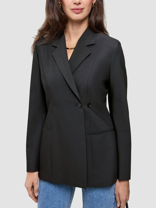 En kvinne som har på seg en svart, dobbeltradet Women’s Avira Blazer-blazer over blå jeans.