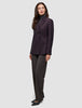 En kvinne har på seg en burgunderfarget Women’s Avira Blazer Burgundy Berry over en grå turtleneck og mørke bukser fra Dansk Design.