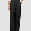 En person som har på seg svarte Avira Pants Wide for damer og en hvit skjorte med knapper.