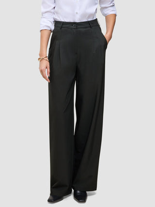 En person som har på seg svarte Avira Pants Wide for damer og en hvit skjorte med knapper.