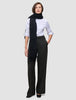 En kvinne har på seg en hvit skjorte med knapper, lange, svarte Women’s Avira Pants Wide Black-bukser og et langt, svart skjerf.