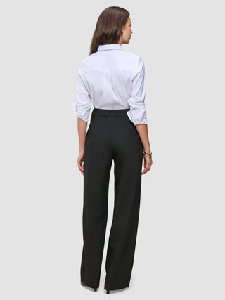 En kvinne sett bakfra, iført en hvit skjorte med knapper og svarte Women’s Avira Pants Wide Black-bukser med høy midje.