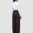 En kvinne kledd i en hvit skjorte med knapper og et par Women’s Avira Pants Wide Burgundy Berry-bukser med høy midje.