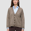 En tykk, myk strikket cardigan i ull for damer i fargen taupe melange, båret over en lyseblå skjorte med krage i klassisk dansk design.
