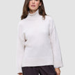 En kvinne iført en off-white, grovstrikket damegenser med høyhals i myk ull, Chunky Soft Wool Knit Turtleneck Sugar Melange.