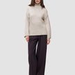 En kvinne har på seg en Women’s Chunky Soft Wool Knit Turtleneck Sugar Melange-genser og mørke bukser med vide ben.