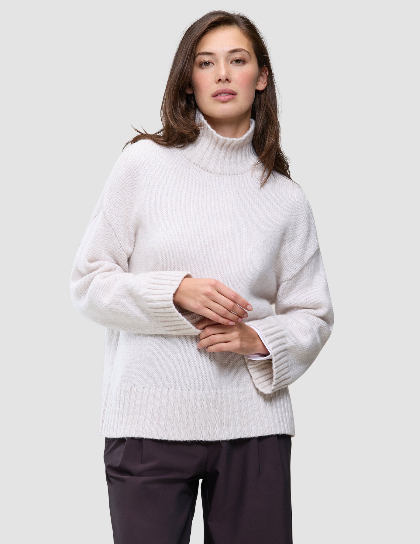 Kvinne iført en Women’s Chunky Soft Wool Knit Turtleneck Sugar Melange, en oversized kremfarget ullgenser.