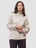 En kvinne iført en Women’s Chunky Soft Wool Knit Turtleneck Sugar Melange, en oversized, lysbeige ribbestrikket turtleneck.