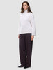 En kvinne kledd i en Women’s Chunky Soft Wool Knit Turtleneck Sugar Melange og mørke bukser med vide ben.