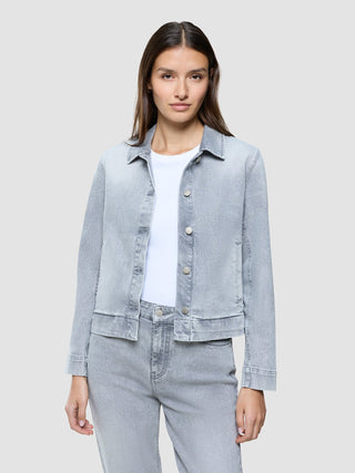 En kvinne har på seg en «Women’s Classic Denim Jacket Light Grey Washed» over en hvit T-skjorte.