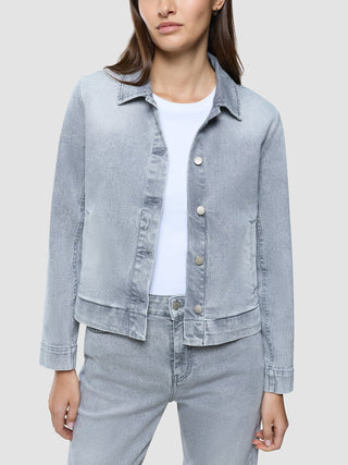 En kvinne som har på seg en «Women’s Classic Denim Jacket Light Grey Washed» over en hvit T-skjorte.