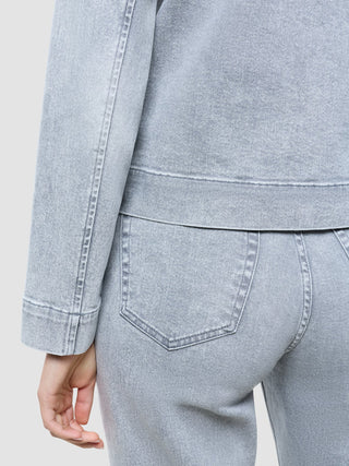 Klassisk denimjakke for kvinner i lysegrå, vasket utførelse, båret over matchende stretch-jeans.