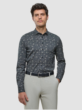 En mann kledd i en «Classic Shirt Grey Floral Regular», et svart belte og lyse bukser.