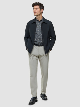 En mann i en svart jakke med glidelås over en «Classic Shirt Grey Floral Regular», lyse bukser og svarte loafers.
