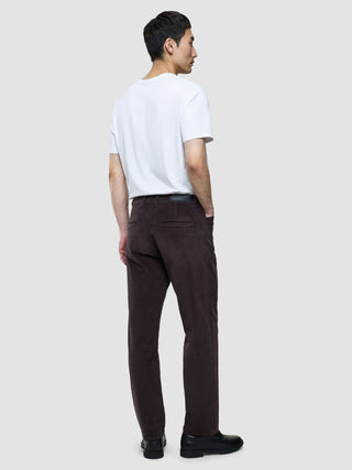 En mann sett bakfra, kledd i en hvit T-skjorte og en corduroy-bukse i «Relaxed Fit Deep Espresso», med hendene i lommene.