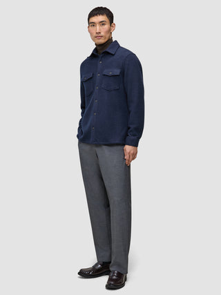 En person iført en dobbeltsidig ullskjorte i mørk marineblå i regular-passform, brun turtleneck, grå bukser og mørke loafers.