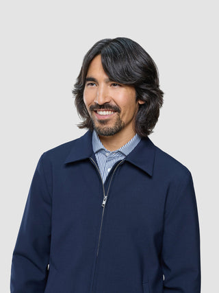 En smilende mann med skjegg, kledd i en marineblå «Ease Jacket Blue Nights» over en stripete skjorte.