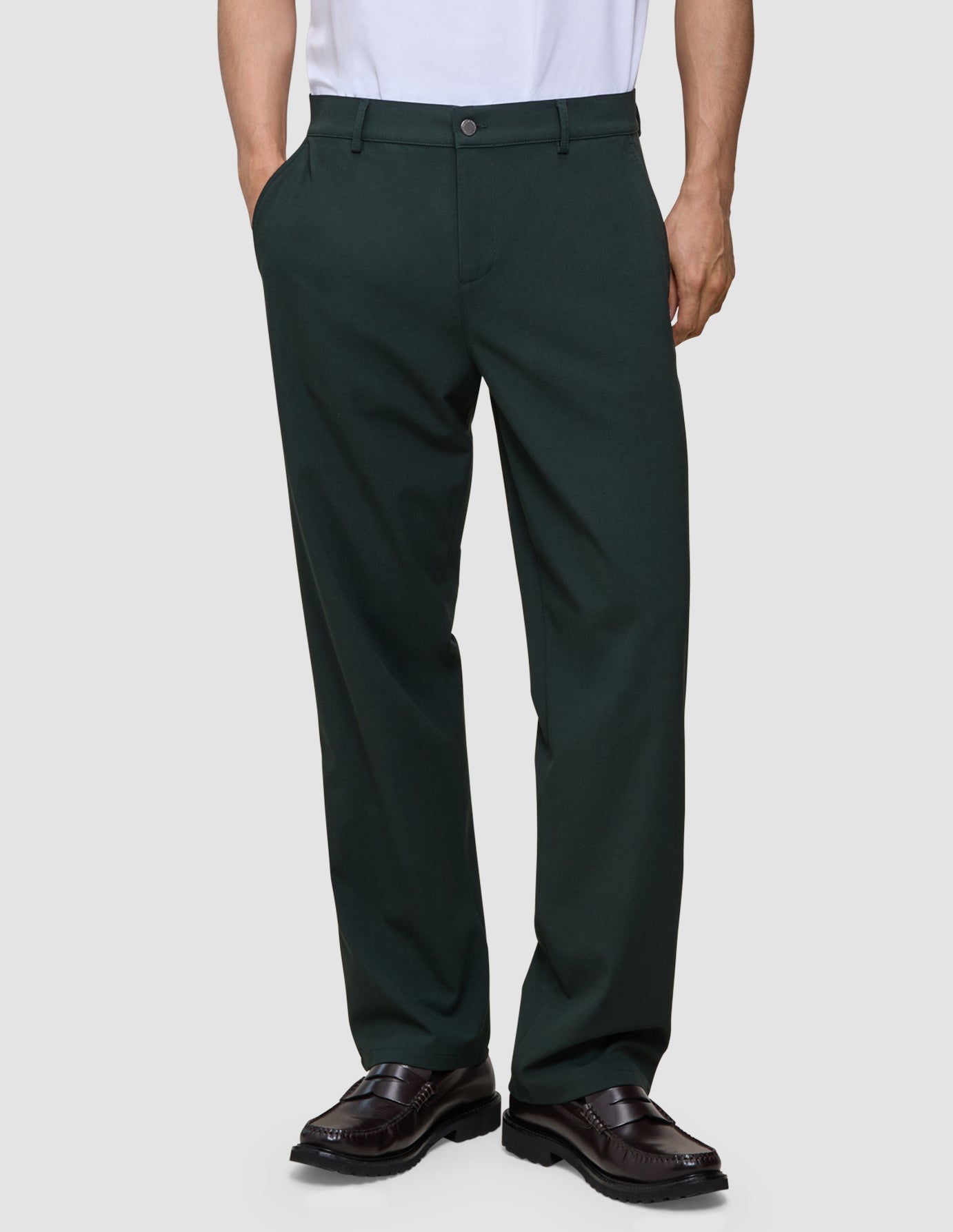 En person som har på seg mørkegrønne Ease Pants Relaxed Fit Northern Pine og brune loafers.