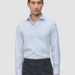En mann kledd i en Elevated Shirt Regular Classic Blue Striped – en lyseblå og hvit stripete bomullsskjorte – og grå bukser.