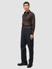 En mann kledd i en Elevated Shirt Regular i mørkebrunt og bukser i antrasittgrått.