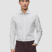 En mann iført en Elevated Shirt Regular Light Grey Striped-skjorte, som er stappet ned i mørke bukser.