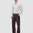 En mann kledd i en Elevated Shirt Regular Light Grey Striped-skjorte og mørkebrune bukser.
