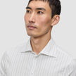 En mann kledd i en Elevated Shirt Regular Light Grey Striped, en elegant hvit skjorte med tynne, grå vertikale striper.