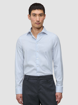 En mann iført en Elevated Shirt Slim Classic Blue Striped i lyseblått og hvitt, som er stappet inn i mørkegrå bukser.